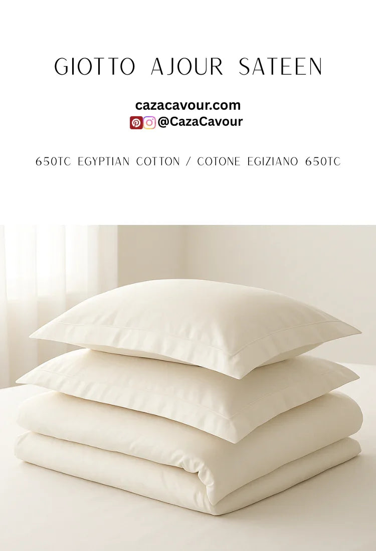 Stack of ivory Egyptian cotton sateen bedding with two pillows and folded duvet on a bed.